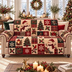 May include: A quilted sofa cover featuring a patchwork design with Christmas motifs including snowmen, pine trees, red cardinals, holly berries, pinecones, and snowflakes in a color palette of cream, forest green, and deep red.