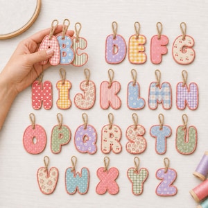May include: A collection of twenty-six fabric alphabet letters, each featuring a unique pattern such as gingham, floral, or polka dots. Each letter is outlined in a coral-coloured border and includes a small jute twine loop for hanging.
