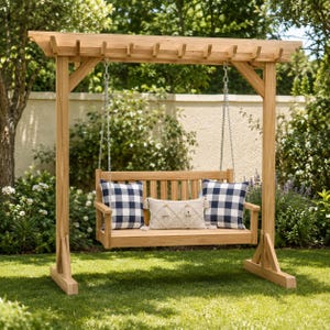 May include: A wooden porch swing with a pergola-style frame, suspended by metal chains. The seat features two navy and white buffalo check pillows on the ends and a cream-colored rectangular throw pillow with a textured diamond pattern in the center.