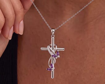 May include: A silver-toned cross pendant necklace featuring a delicate, swirling metal vine design adorned with small, clear pavé stones and two marquise-cut purple amethyst-colored gemstones shaped like butterfly wings.