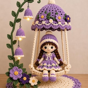 May include: A crocheted doll with brown braided hair wearing a purple dress and hat, sitting on a swing under a purple canopy. A green vine stand features three hanging bell-shaped lights and purple and white flowers on a round base.
