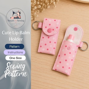 Könnte beinhalten: Zwei hellrosa Lippenbalsam-Halter aus Stoff mit einem Muster aus weißen Blumen und Punkten. Jeder Halter hat einen seitlichen Metallring und einen rosa Druckknopfverschluss. Einer ist geschlossen, der andere offen mit einem Lippenbalsam darin.