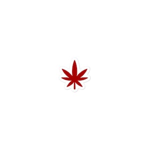 May include: A sticker featuring a solid dark red cannabis leaf graphic with a distinct white border outline. The design is centered and symmetrical, showcasing the iconic seven-pointed leaf shape in a bold, flat color against a plain background.