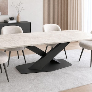 May include: A rectangular dining table with a light grey stone-textured top and a black metal base featuring two intersecting diagonal supports on a flat, oblong pedestal. The table is surrounded by four light beige upholstered chairs.