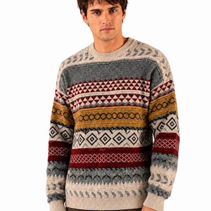 May include: A long-sleeve crew neck sweater featuring a horizontal multi-colored pattern with bands of cream, grey, mustard yellow, and deep red. The knit design includes geometric shapes, diamonds, and chevron stripes across the chest and sleeves.