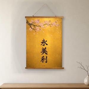 May include: A vertical wall hanging scroll featuring a gold background with a branch of pink cherry blossoms at the top. The center displays black Japanese kanji characters arranged vertically, with the name Emily printed in small black text below.