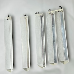 May include: Four clear, rectangular crystal chandelier prisms with faceted edges and a small metal hook at the top for hanging. The prisms are suspended against a white background, showcasing their reflective qualities.
