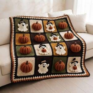 May include: A square crochet blanket featuring a grid of alternating squares in cream, dark brown, and olive green. The blanket is decorated with three-dimensional crocheted pumpkins in burnt orange and white ghosts wearing black witch hats.