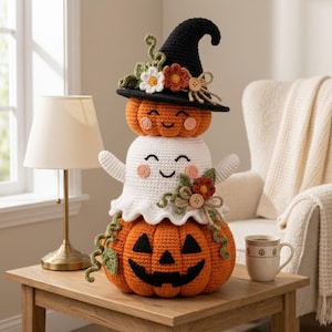 May include: A stacked crochet decoration featuring a large orange jack-o'-lantern base, a white ghost in the middle, and a small orange pumpkin wearing a black witch hat on top. The figures are adorned with crocheted flowers, green vines, and wooden buttons.