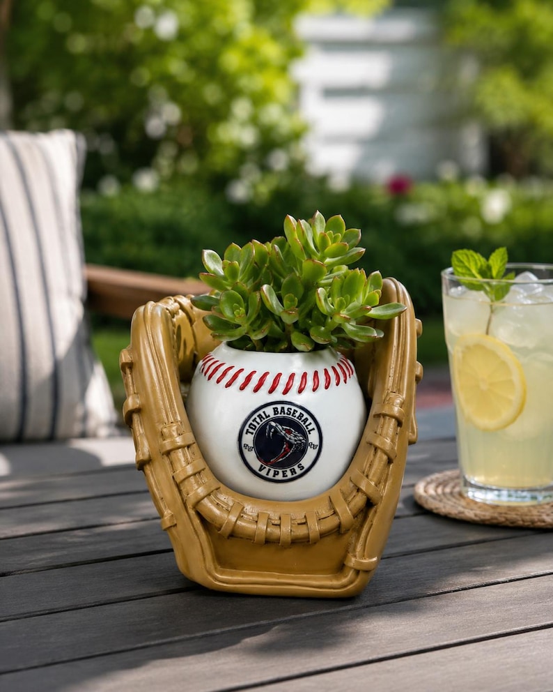 May include: A tan ceramic baseball glove planter holding a green succulent. The center features a white baseball with red stitching and a circular logo that reads Total Baseball Vipers with a snake graphic in the center of the emblem.