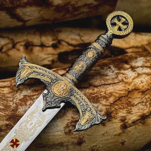 Può includere: Una spada decorativa con elsa color argento e oro con intricati motivi in rilievo ed emblemi circolari. La guardia presenta dettagli ornamentali, mentre la lama è incisa con volute dorate e un simbolo a croce di colore rosso e oro.