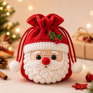 Pode incluir: Uma bolsa de crochê vermelha e branca com cordão, desenhada como o Pai Natal. A bolsa apresenta uma barba branca, um nariz vermelho, olhos pretos e uma aba de gorro branca. Uma pequena folha de azevinho verde com três bagas vermelhas está presa.
