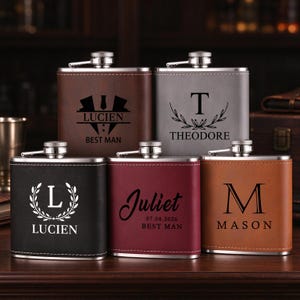May include: Five rectangular metal flasks wrapped in faux leather in brown, grey, black, maroon, and tan. Each flask features a silver screw-top lid and custom laser-engraved text and graphics, including names like Lucien, Theodore, Juliet, and Mason.