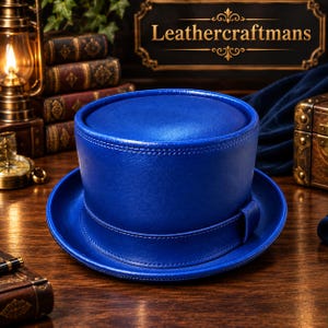 Peut inclure: Un haut-de-forme bleu roi vif fabriqué en cuir lisse. Le chapeau présente une calotte circulaire plate, un corps cylindrique structuré et un large bord. Une bande en cuir assortie entoure la base de la calotte, fixée par une petite boucle.