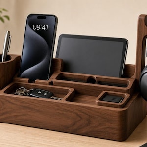 Puede incluir: Un organizador de escritorio de madera oscura que incluye un portalápices cilíndrico, una ranura vertical para smartphone, una ranura horizontal para tableta, un compartimento cuadrado pequeño, una bandeja rectangular para llaves y un gancho lateral para auriculares.