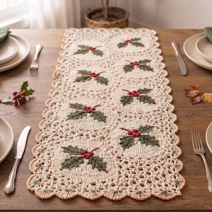 Può includere: Un runner da tavola rettangolare all'uncinetto color crema con un motivo ripetuto di foglie di agrifoglio verdi ricamate e bacche rosse. Il runner presenta un bordo smerlato con intricati dettagli traforati nel design tessile.