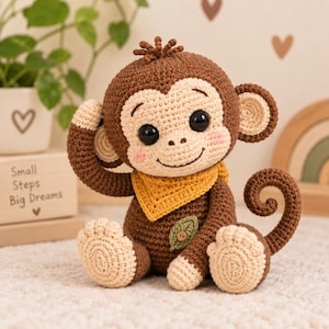 May include: A crocheted monkey toy with dark brown and cream yarn, featuring large black safety eyes, pink cheeks, a yellow triangular neck scarf, and a small green leaf applique on its chest. The monkey has a curled tail and sits upright.