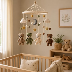 May include: A hanging nursery mobile featuring four crocheted teddy bears in brown, olive green, cream, and dark brown. The mobile includes crocheted clouds, stars, and a crescent moon, all suspended from a circular frame with white yarn strings.