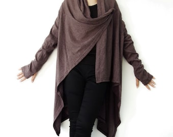May include: A draped, brown cardigan with long sleeves and an asymmetrical hemline. The cardigan is paired with black pants and brown leather sandals. The outfit is set against a white background.