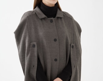 May include: A gray ribbed knit cape with a button closure and long sleeves. The cape has a collar and is made of a soft, comfortable fabric.