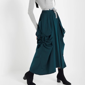 Op de afbeelding: Een tealgroene maxi-rok met een geplooide, volumineuze vorm. De rok heeft een trekkoord in de taille en een lange, vloeiende silhouet.