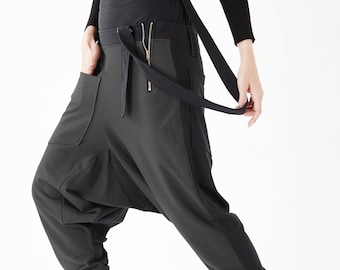 May include: Black and gray high-waisted pants with a unique design featuring a wide waistband, two pockets, and a strap that can be tied around the waist. The pants have a loose, baggy fit.