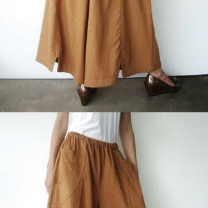 May include: A pair of brown wide-leg pants with a high waist and side slits. The pants have pockets on the front and are made of a lightweight fabric.