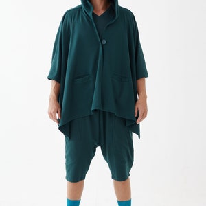 May include: A teal hooded cardigan with a single button closure and two pockets. The cardigan is worn over teal shorts and teal socks. The person is wearing white sandals.