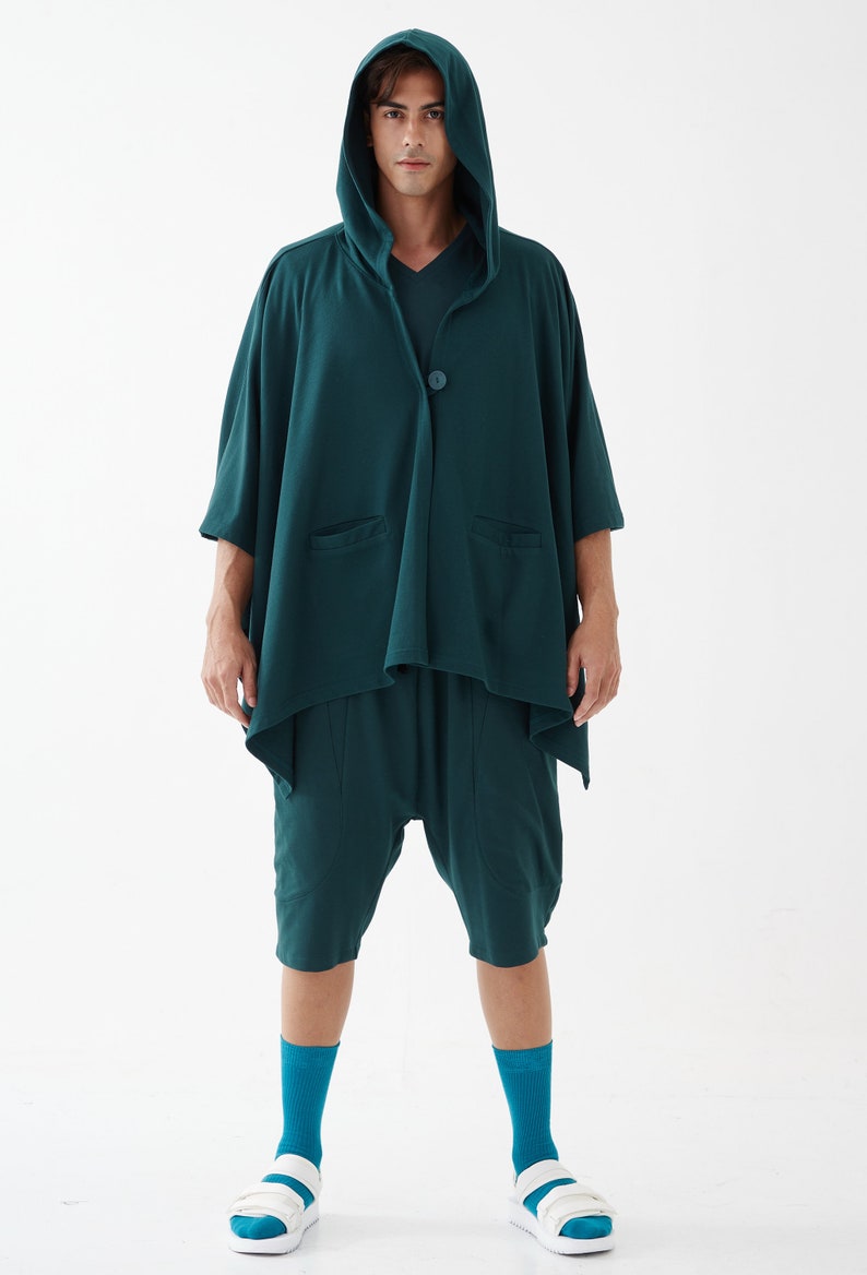 May include: A teal hooded cardigan with a single button closure and two pockets. The cardigan is worn over teal shorts and teal socks. The person is wearing white sandals.