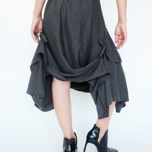 May include: A charcoal gray skirt with a flowing, asymmetrical design. The skirt has a gathered waistband and a loose, comfortable fit.