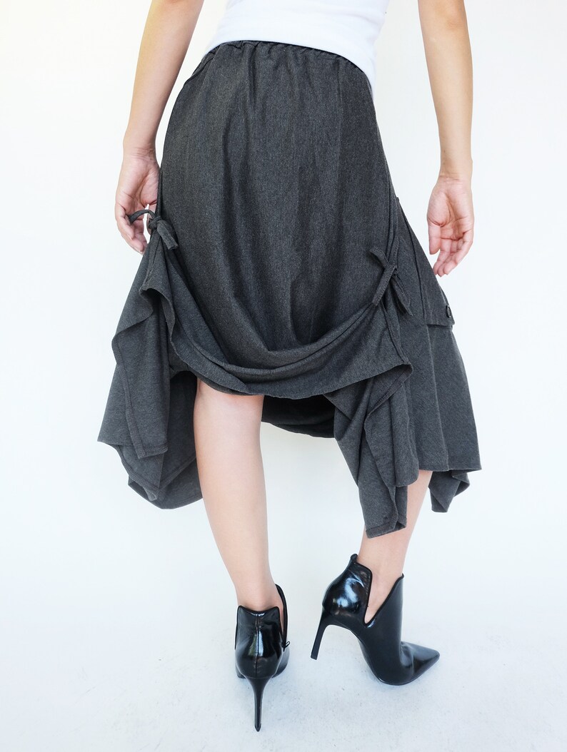 May include: A charcoal gray skirt with a flowing, asymmetrical design. The skirt has a gathered waistband and a loose, comfortable fit.