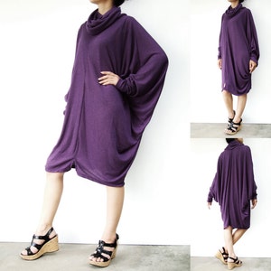 Puede incluir: Un vestido largo de t&uacute;nica de color morado con cuello de tortuga y mangas largas. El vestido est&aacute; hecho de una tela suave y el&aacute;stica y tiene un corte holgado. La modelo lleva el vestido con sandalias negras.