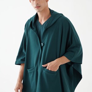 May include: A dark green hooded cardigan with a single button closure and two pockets. The cardigan is made of a soft, comfortable fabric.