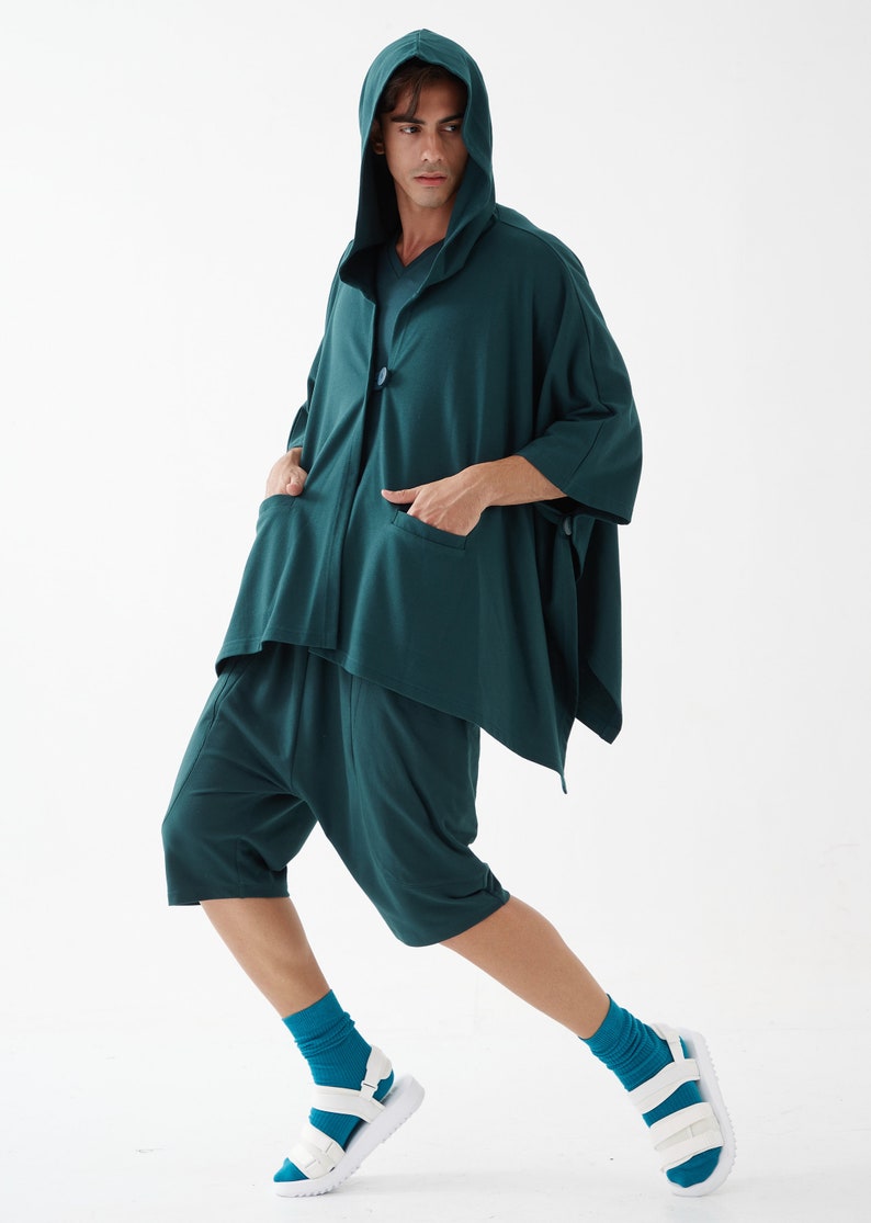 May include: A teal hooded top with a single button closure and matching teal shorts. The person is wearing teal socks and white sandals.