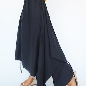 May include: A black asymmetrical skirt with a drawstring waist and side pockets. The skirt is made of a lightweight fabric and has a flowing silhouette.