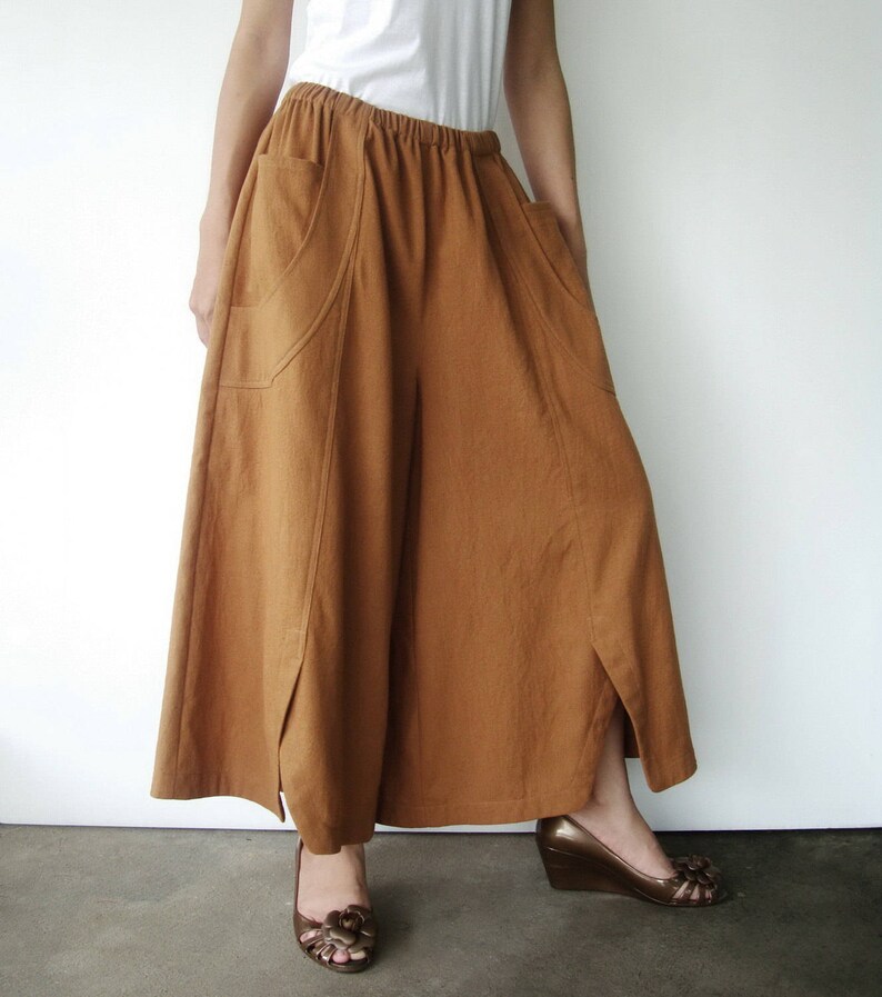 May include: A long, brown skirt with two large pockets and a slit on each side. The skirt is made of a soft, textured fabric and has a relaxed fit.