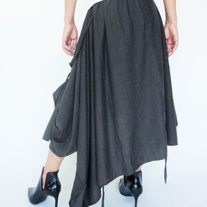 May include: A gray asymmetrical skirt with a long, flowing design. The skirt has a gathered detail at the waist and a long, flowing train.