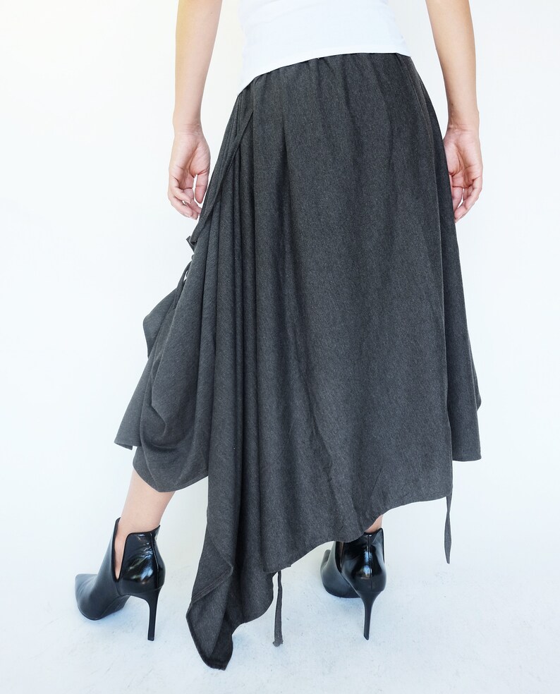 May include: A gray asymmetrical skirt with a long, flowing design. The skirt has a gathered detail at the waist and a long, flowing train.
