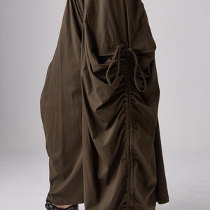 May include: A pair of brown wide-leg pants with a drawstring detail on the side. The pants are made of a soft, flowing fabric and have a relaxed fit.