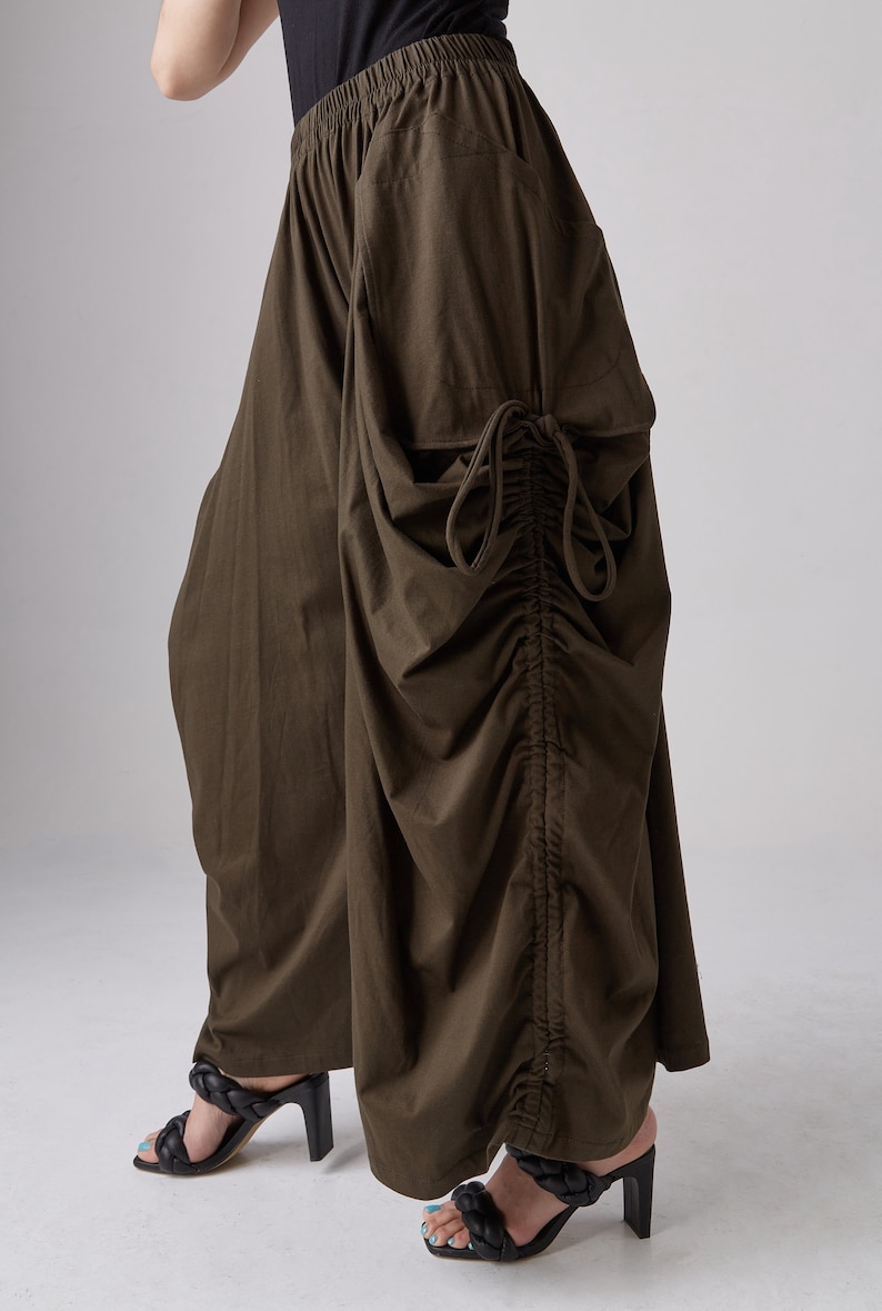 May include: A pair of brown wide-leg pants with a drawstring detail on the side. The pants are made of a soft, flowing fabric and have a relaxed fit.