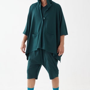 May include: A teal hooded cardigan with a single button closure and two pockets. The cardigan is worn over a teal pair of shorts. The person is wearing teal socks and white sandals.