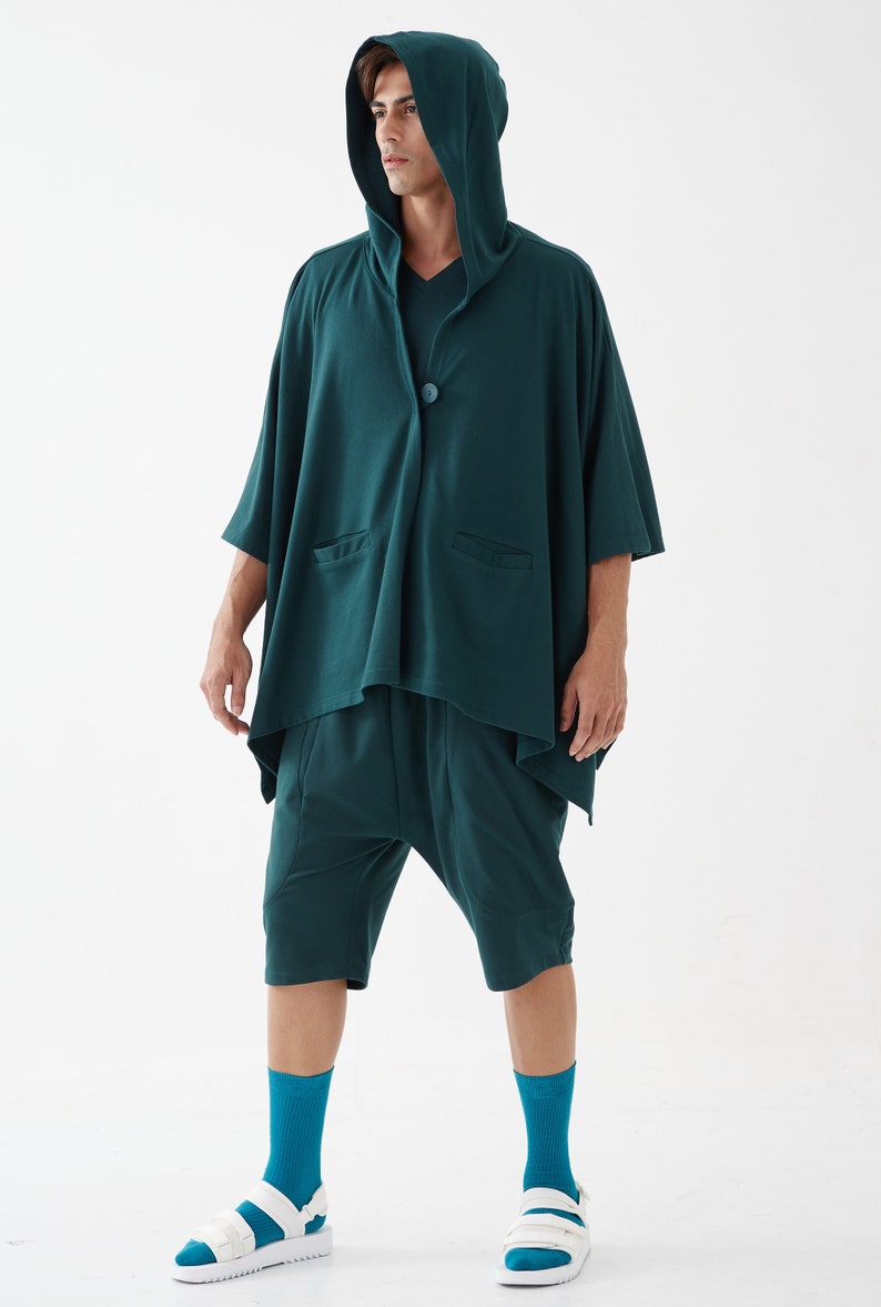 May include: A teal hooded cardigan with a single button closure and two pockets. The cardigan is worn over a teal pair of shorts. The person is wearing teal socks and white sandals.
