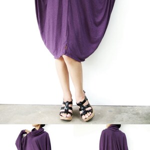Puede incluir: Un vestido t&uacute;nica largo y holgado de color morado con cuello de pico y mangas largas. El vestido est&aacute; hecho de una tela suave y el&aacute;stica y tiene un ajuste holgado. La modelo lleva el vestido con leggings negros y sandalias negras.