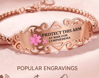 May include: A rose gold medical alert bracelet featuring a decorative filigree plate engraved with the text PROTECT THIS ARM AT RISK FOR LYMPHEDEMA and a pink medical symbol with a ribbon. The bracelet has a delicate chain and a lobster clasp.