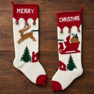Könnte beinhalten: Zwei gestrickte Weihnachtsstrümpfe in Weiß und Rot. Der linke Strumpf zeigt das Wort MERRY, ein braunes Rentier, einen grünen Baum und ein rotes Haus. Der rechte zeigt das Wort CHRISTMAS, einen roten Schlitten, einen grünen Baum und ein rotes Haus.