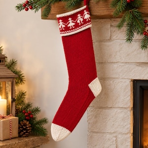 Könnte beinhalten: Ein roter Strick-Weihnachtsstrumpf mit weißem Umschlag, der ein wiederkehrendes Muster aus Figuren zeigt, die sich an den Händen halten. Der Strumpf hat eine weiße Ferse und eine weiße Spitze aus geripptem Strick mit einer Aufhängeschlaufe.