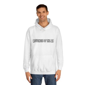 May include: A white long-sleeve hooded sweatshirt featuring a front kangaroo pocket and the text REVENGE OF THE AI printed in black, bold, outlined capital letters across the chest area, paired with dark blue denim jeans.