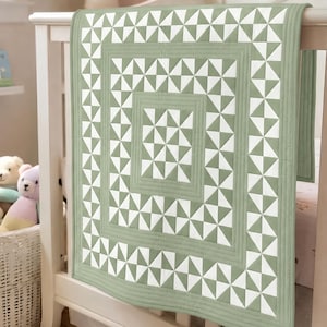 May include: A sage green and white quilt featuring a geometric pinwheel pattern arranged in concentric square borders. The design consists of alternating triangular blocks of solid sage green and white fabric, finished with straight-line quilting.