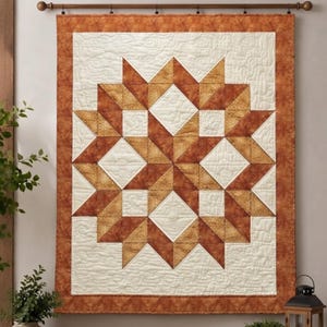 May include: A rectangular wall quilt featuring a central star pattern composed of cream and burnt orange fabric pieces. The quilt has a wide burnt orange border and is decorated with intricate, swirling machine-stitched quilting patterns throughout.