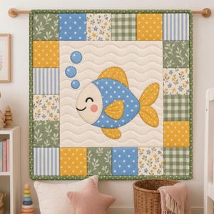 Könnte beinhalten: Ein quadratischer Wandbehang-Quilt mit einem cremefarbenen Mittelteil, einer blauen Fisch-Applikation mit Punkten und drei blauen Blasen. Der Rand besteht aus einem Patchwork aus gelben, blauen und grünen Quadraten mit Blumen-, Streifen- und Karomustern.
